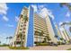 Low angle view of condo exterior with blue architectural accents and surrounding mature landscaping at 14950 Gulf Blvd # 404, Madeira Beach, FL 33708
