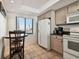 Eat-in kitchen features tan tile flooring, a window and standard appliances at 14950 Gulf Blvd # 404, Madeira Beach, FL 33708