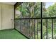 Screened balcony with artificial turf and lush greenery views at 3300 Fox Chase N Cir # 231, Palm Harbor, FL 34683