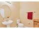 Small bathroom with pedestal sink, toilet and a round mirror at 8863 Bella Vita Cir, Land O Lakes, FL 34637