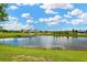 Scenic community lake with lush green landscaping and clubhouse in the background at 8863 Bella Vita Cir, Land O Lakes, FL 34637