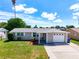 Ranch-style home with a gray exterior, attached garage, and manicured lawn at 2248 Society Dr, Holiday, FL 34691
