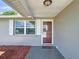 Home's front entrance with a reddish-brown door and white shutters at 2248 Society Dr, Holiday, FL 34691