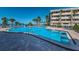 Community pool with surrounding lounge chairs and tropical landscaping near building at 100 Bluff View Dr # 405C, Belleair Bluffs, FL 33770