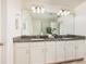 Elegant bathroom featuring a double vanity, granite countertop, and bright lighting at 17860 Althea Blue Pl, Lutz, FL 33558