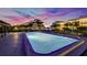 Inviting community pool at sunset with surrounding landscape lighting at 50 Coe Rd # 125, Belleair, FL 33756