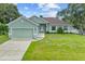 Front view of a light green house with a brown roof, garage, and nicely landscaped lawn at 105 Dartmouth Rd, Venice, FL 34293
