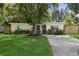 White house with green lawn, mature tree, and wooden accents at 1058 60Th N Ave, St Petersburg, FL 33703