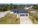 An aerial view of a well-maintained home with a three-car garage and an expansive green lawn at 14346 San Domingo Blvd, Port Charlotte, FL 33981