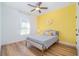 Bright bedroom with a yellow accent wall, white curtains, wood-look floors, and a ceiling fan at 14346 San Domingo Blvd, Port Charlotte, FL 33981