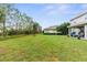 View of the large backyard highlighting a covered patio, lush greenery, and exterior of home at 32924 Estate Garden Dr, Wesley Chapel, FL 33545