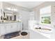 Bright bathroom with a large soaking tub, glass shower, and double vanity with white cabinets at 32924 Estate Garden Dr, Wesley Chapel, FL 33545