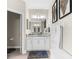 Clean bathroom with white cabinets, a gray rug, and a large mirror complemented by tasteful decorations at 32924 Estate Garden Dr, Wesley Chapel, FL 33545