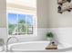 Close-up of a soaking tub next to a window with a view and decorative shelves enhance this bathroom's ambiance at 32924 Estate Garden Dr, Wesley Chapel, FL 33545