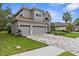 A two-story home featuring a three-car garage, a paver driveway, stucco facade and well-manicured landscaping at 32924 Estate Garden Dr, Wesley Chapel, FL 33545
