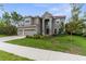 Elegant two-story home with a three-car garage, lush lawn, and mature trees at 32924 Estate Garden Dr, Wesley Chapel, FL 33545