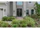 Close-up of front entrance showcasing the black double door and manicured landscaping at 32924 Estate Garden Dr, Wesley Chapel, FL 33545