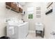 Bright laundry room featuring white washer and dryer, shelving with wicker baskets, and a utility sink at 32924 Estate Garden Dr, Wesley Chapel, FL 33545