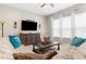Comfortable living room with a plush sofa, a flat-screen TV mounted above a wooden cabinet, and large bright windows at 32924 Estate Garden Dr, Wesley Chapel, FL 33545