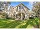The back exterior of the house shows a covered patio with chairs and expansive lawn at 13929 Lake Fishhawk Dr, Lithia, FL 33547