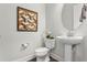 Cozy bathroom featuring a pedestal sink, modern toilet, and decorative wall art at 13929 Lake Fishhawk Dr, Lithia, FL 33547