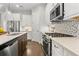 Well-equipped kitchen with stainless steel appliances, white cabinetry, and a mosaic backsplash at 13929 Lake Fishhawk Dr, Lithia, FL 33547