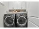 Modern laundry room with gray front-load washer and dryer and white cabinets for storage at 13929 Lake Fishhawk Dr, Lithia, FL 33547
