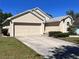 Tan home with a two-car garage and landscaped front yard under a clear blue sky at 418 Henderson Ave, Seffner, FL 33584