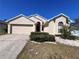 Inviting home featuring a two-car garage, manicured lawn, mature landscaping, and a welcoming front entrance at 418 Henderson Ave, Seffner, FL 33584