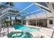 Beautiful screened-in pool area with a spa, surrounded by lush landscaping and brick pavers, perfect for outdoor entertaining at 181 Sportsman Rd, Rotonda West, FL 33947
