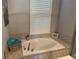 Bathroom featuring soaking tub with tile surround and window with shutters at 4749 Stoneview Cir, Oldsmar, FL 34677