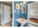 Stylish bathroom with a classic pedestal sink, bright blue accent wall, and decorative mirror at 7226 13Th N St, St Petersburg, FL 33702