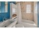 Bathroom featuring a bathtub, shower, window, white shelves, light blue accent wall and tan tile at 7226 13Th N St, St Petersburg, FL 33702
