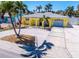 Charming yellow home features a one car garage, an arched entryway, and lush tropical landscaping at 855 Boca Ciega Isle Dr, St Pete Beach, FL 33706