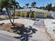 Charming yellow home featuring a driveway and tropical landscaping with palm trees and white gravel at 855 Boca Ciega Isle Dr, St Pete Beach, FL 33706