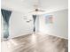 Bright bedroom with gray wood floors, a ceiling fan, and natural light from two windows at 9100 Suffolk Ln, Port Richey, FL 34668