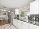 Cozy kitchen with white cabinets, stainless steel refrigerator, and a partial view to dinette table at 9100 Suffolk Ln, Port Richey, FL 34668