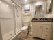 Bright bathroom featuring a tiled shower, toilet, and vanity with granite counters and decorative blue-tiled mirror at 900 Harbour House Dr, Indian Rocks Beach, FL 33785