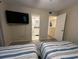 Comfortable bedroom featuring two beds, a mounted TV, and an ensuite bathroom that offers a private retreat at 900 Harbour House Dr, Indian Rocks Beach, FL 33785