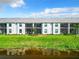 Back of condo units with well-kept lawns and landscaping reflected beautifully in the tranquil lake water at 14204 Heritage Landing Blvd # 714, Punta Gorda, FL 33955