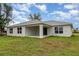 Exterior of home with a covered patio, set against a grassy backyard and blue sky with some clouds at 3067 Newbury St, Port Charlotte, FL 33952