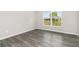 Bedroom features gray wood-look flooring and a window overlooking the green backyard at 3067 Newbury St, Port Charlotte, FL 33952