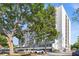 A striking exterior view showcases the towering condominium building with mature trees in front and visible parking at 3211 W Swann Ave # 808, Tampa, FL 33609