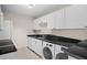 Efficient kitchen with white cabinetry, black granite countertops, stainless steel sink, and in-unit washer and dryer at 3211 W Swann Ave # 808, Tampa, FL 33609