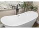 Close-up of a sleek, stand-alone bathtub with modern black fixtures and beach themed decor at 4301 Hudson Ln, Tampa, FL 33618