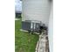 Exterior A/C unit on a concrete slab surrounded by green grass and a stone walkway at 3124 Pond Hollow St # 183, Wesley Chapel, FL 33543