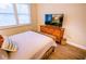 Bright bedroom with a wicker bed frame, warm wood dresser, and modern television at 5169 Oxford Dr, Sarasota, FL 34242