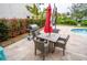 Relaxing patio area with a grill, outdoor dining set, umbrella, and tropical landscaping at 5169 Oxford Dr, Sarasota, FL 34242
