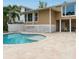 Back exterior showcasing a kidney-shaped pool, patio and tan two-story home at 5169 Oxford Dr, Sarasota, FL 34242