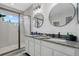 Bright bathroom with double vanity, granite countertops, round mirrors, and a glass-enclosed shower at 7114 Mill Hopper Ct, Palmetto, FL 34221